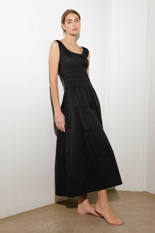 Woman wearing a black dress against a white wall