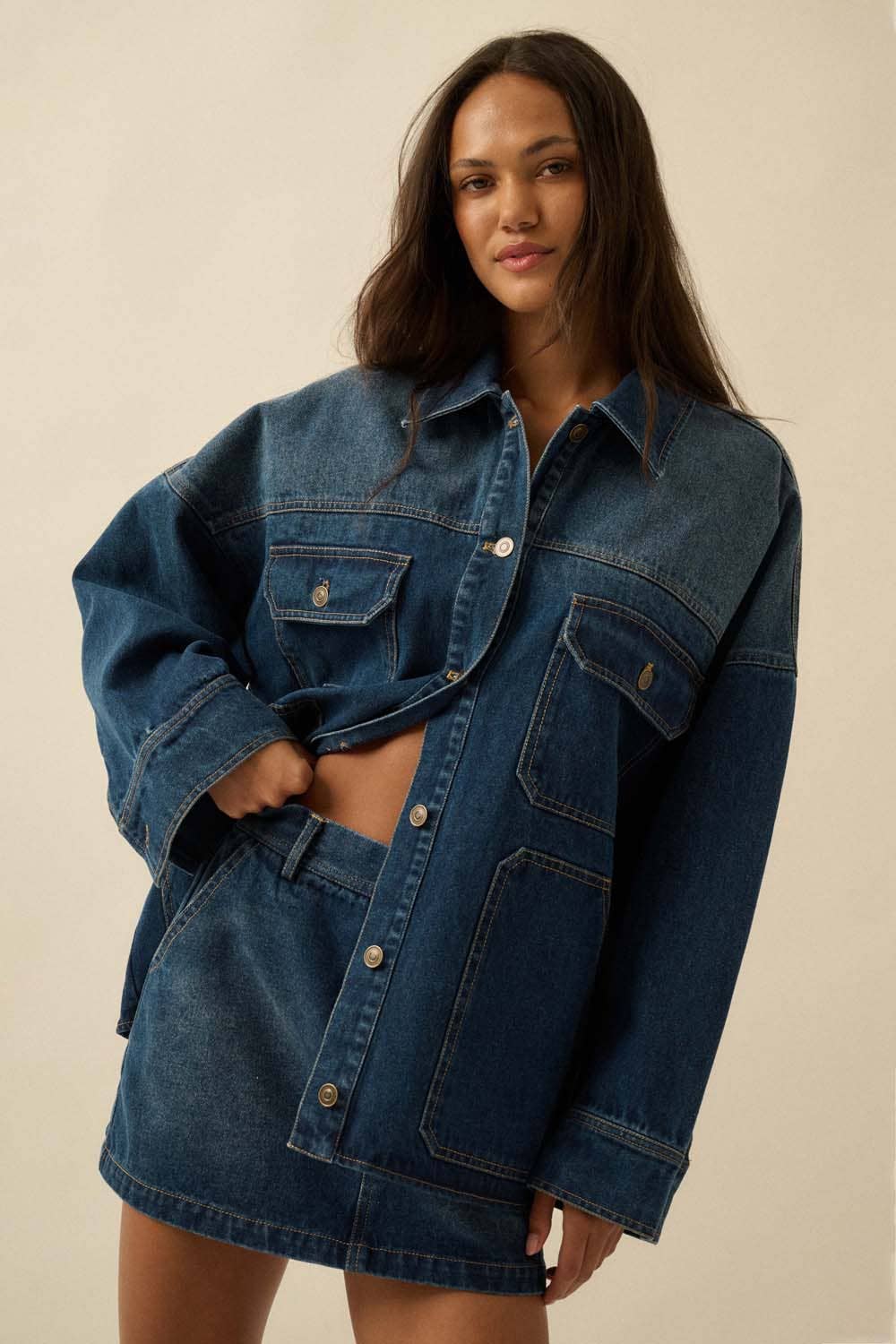 Woman wearing a blue denim jacket and skirt on a beige background