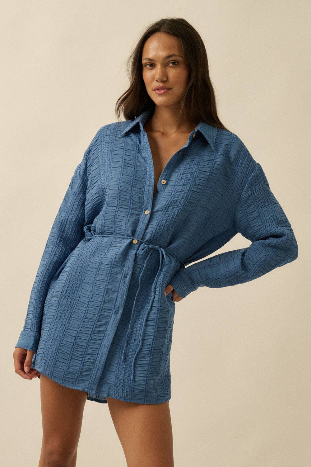 Woman wearing a blue textured dress against a beige background