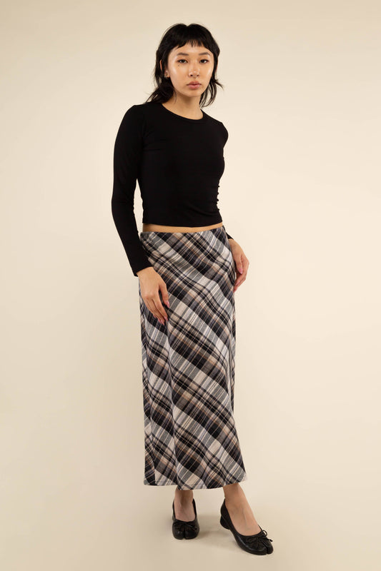 Woman wearing a black top and plaid skirt on a beige background