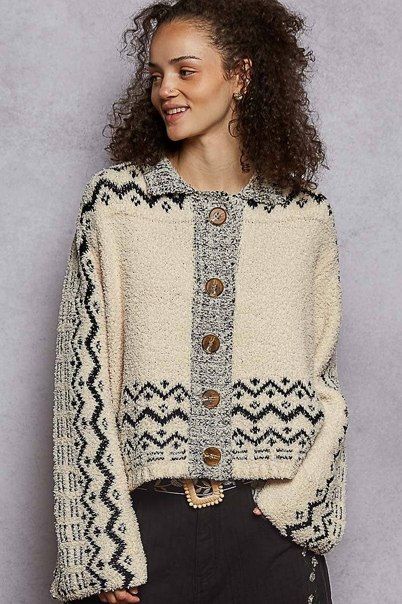 Woman wearing a patterned cardigan with wooden buttons against a gray background
