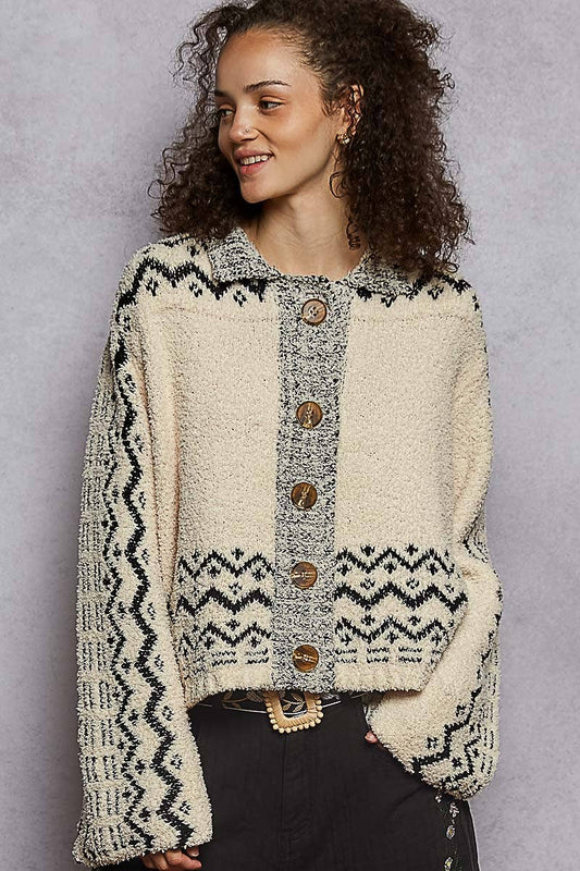 Woman wearing a patterned cardigan with wooden buttons against a gray background