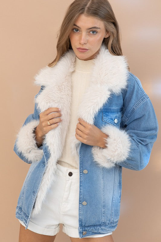 Woman wearing a denim jacket with white fur trim on a beige background