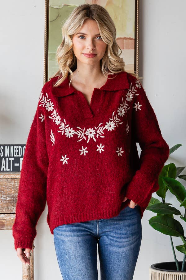 Woman wearing a red sweater with white floral patterns indoors.