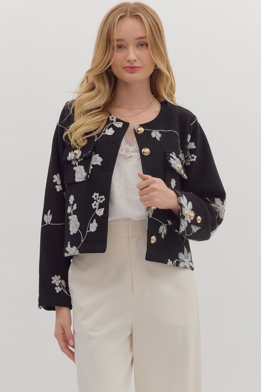 Woman wearing a black floral embroidered jacket on a white background