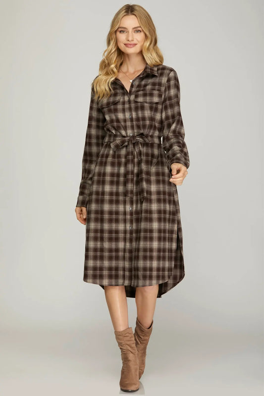 Woman wearing a plaid dress with a belt on a plain background