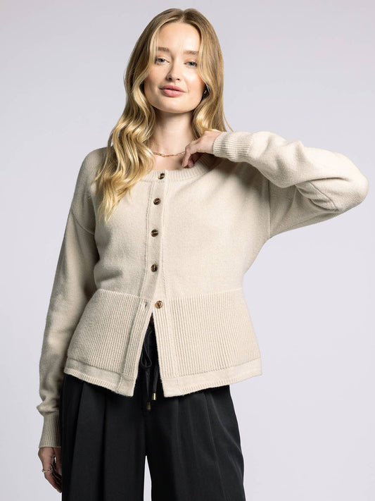 Woman wearing a beige cardigan on a light gray background