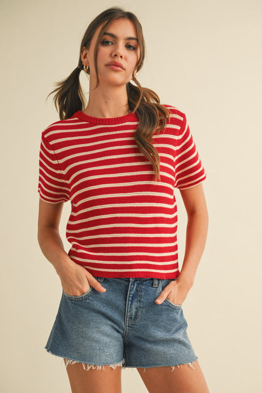 Woman wearing a red and white striped shirt and denim shorts on a beige background