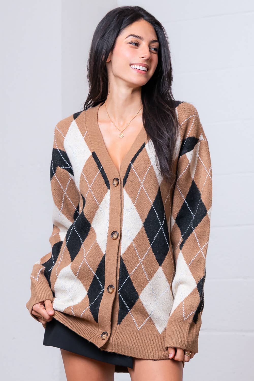 Woman wearing a brown argyle cardigan against a plain background