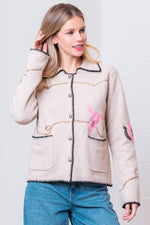 Woman wearing a beige jacket with pink accents on a white background