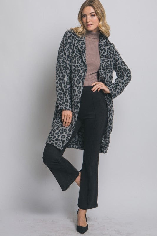 Woman wearing a leopard print coat over a black outfit on a plain background
