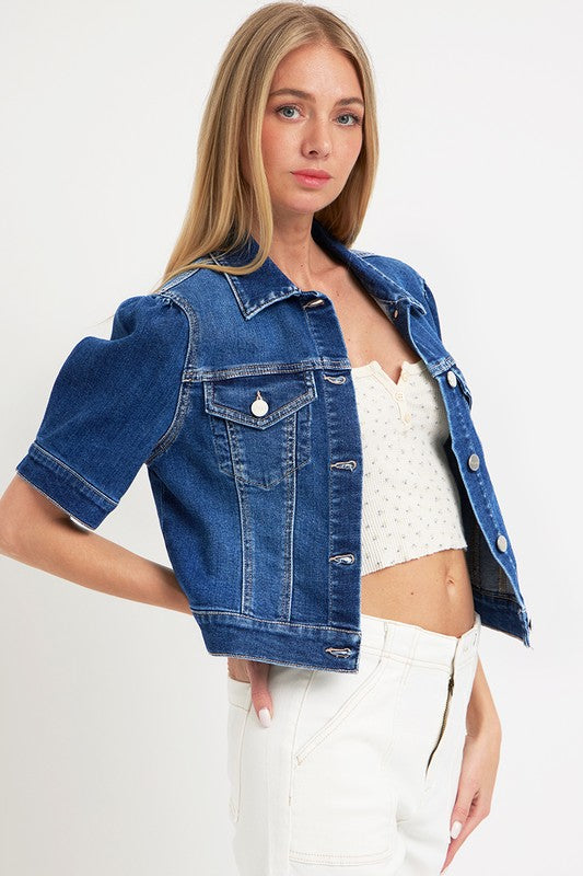 Woman wearing a blue denim jacket over a white top and pants on a white background