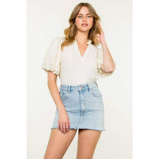 Woman wearing a white blouse and denim skirt on a plain background