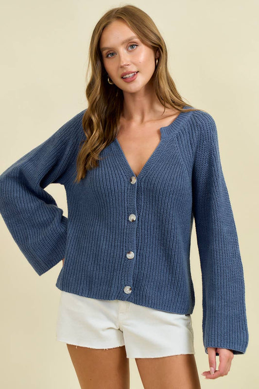 Woman wearing a blue cardigan over white shorts on a beige background