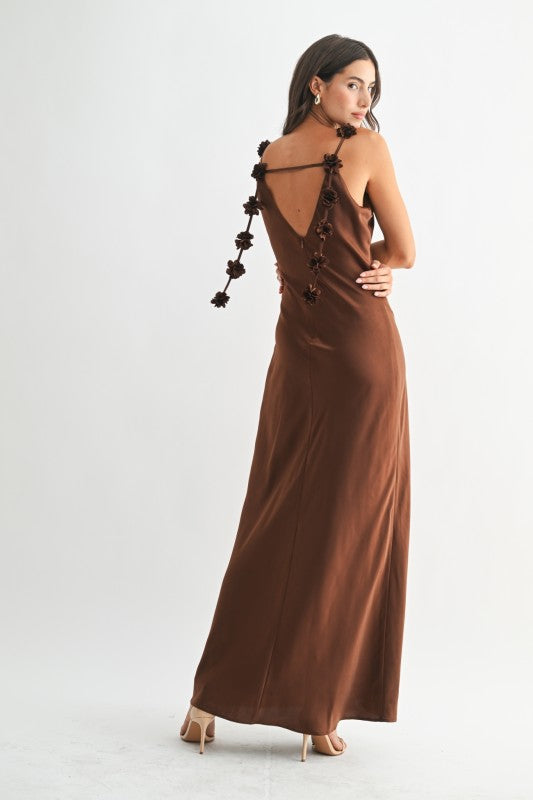 Woman wearing a brown evening gown with floral details on a white background