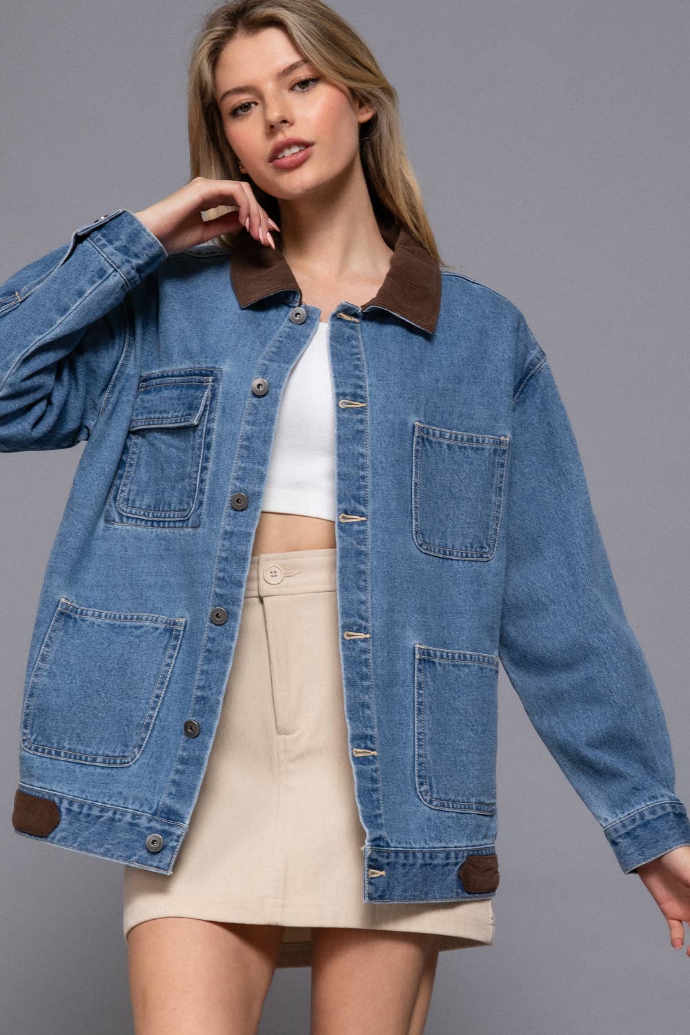 Woman wearing a blue denim jacket with brown collar and trim on a gray background