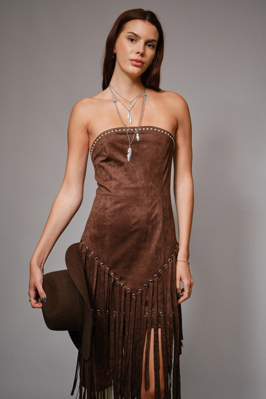 Woman wearing a brown strapless dress with fringe details on a gray background