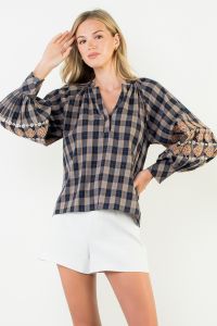 Woman wearing a plaid blouse with sheer sleeves on a white background