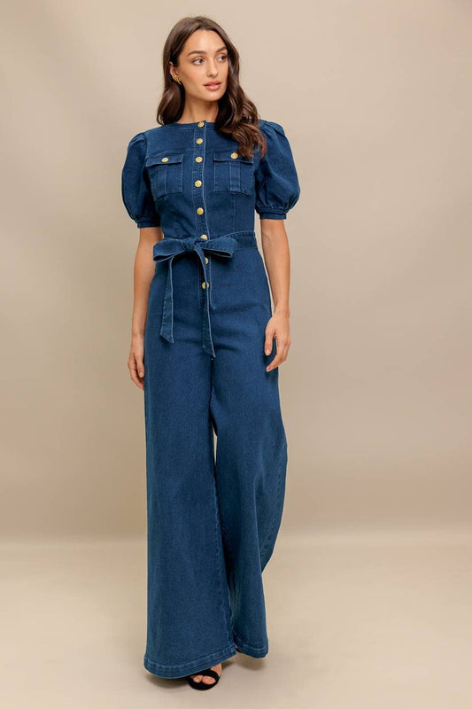 Woman wearing a blue denim jumpsuit on a beige background