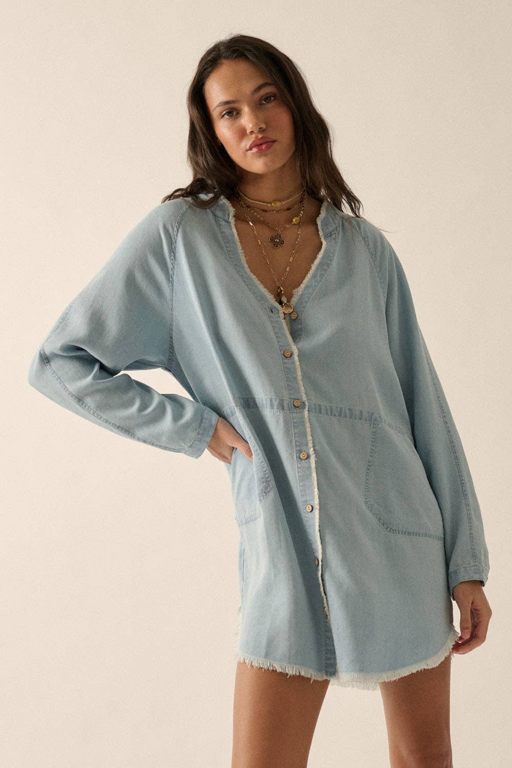 Woman wearing a light blue denim shirt against a beige background
