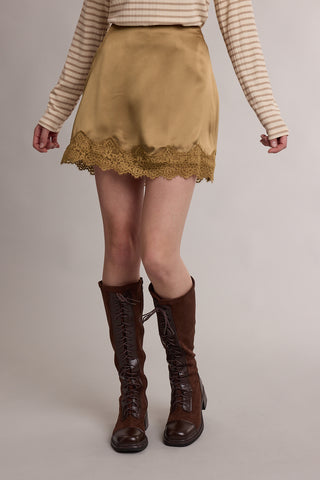 Tan satin mini skirt with lace trim hem, styled with knee-high brown lace-up boots