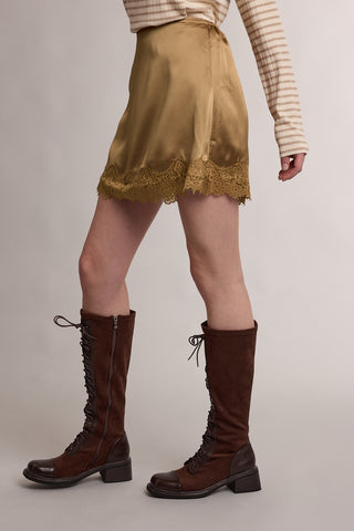 Tan satin mini skirt with lace trim hem, styled with knee-high lace-up boots