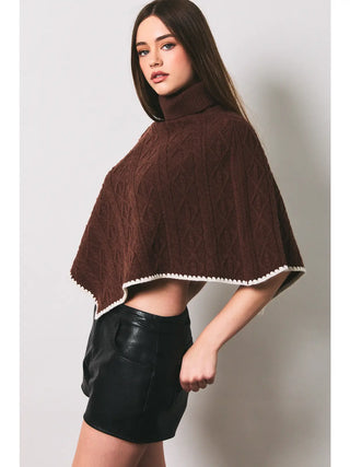 Brown cable knit turtleneck poncho sweater with cream trim, cropped length