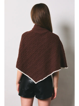 Brown cable knit poncho with white crochet trim and turtleneck collar