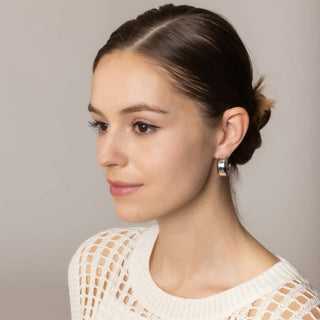 Chunky silver half hoop post earrings worn by brunette model with updo