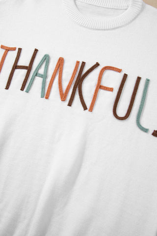 White crew neck sweater with multicolor embroidered THANKFUL lettering across chest