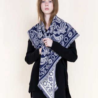 Navy blue and white paisley triangular scarf with fringe edges draped over shoulders