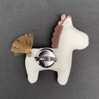 Back view of white linen-cotton horse brooch with brown mane, tassel tail, and pin clasp