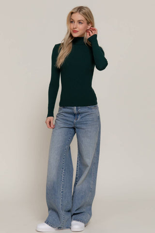 Forest green ribbed turtleneck long sleeve fitted sweater paired with wide leg jeans