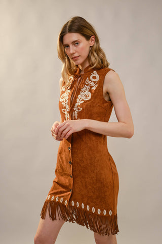 Brown suede sleeveless mini dress with white embroidery, fringe hem, and snap buttons