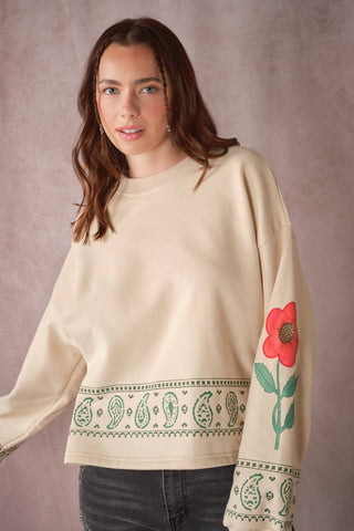 Cream oversized sweatshirt with green paisley border and red floral sleeve graphic
