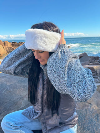 White faux fur headband worn by woman at rocky ocean shoreline in winter