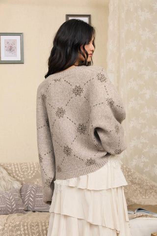 Taupe knit cardigan with snowflake jacquard diamond pattern, worn over white ruffle skirt