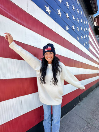 Navy knit beanie with American flag chenille patch and faux fur pom