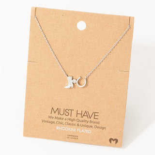Silver rhodium-plated necklace with cowboy boot and horseshoe charms on kraft card