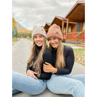 Women wearing taupe and pink boucle knit cuff beanies with small logo patch