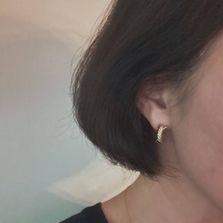 Small gold twisted rope hoop earrings worn on ear with short dark hair