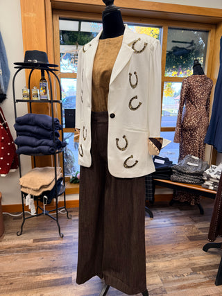 Ivory blazer with gold horseshoe appliqués displayed over tan top and brown wide-leg pants