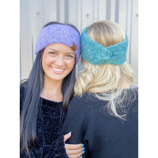 Two women wearing C.C Beanie twisted headbands in purple and teal marled yarn