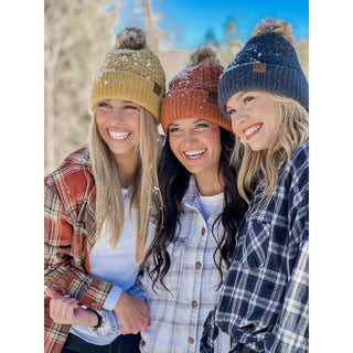 C.C Beanie smocked stitch pom beanies in gold, orange, and navy worn outdoors in snow
