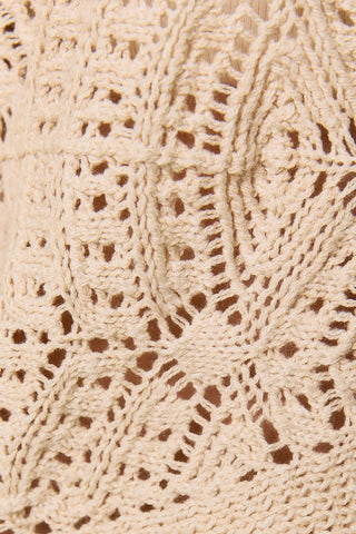 Close-up of oatmeal crochet knit fabric with open-weave floral pattern