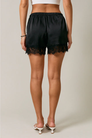 Black satin lounge shorts with lace trim hem, elastic waist, back view
