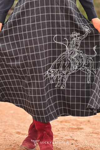 Black plaid flannel skirt with white bull rider embroidery, worn with red cowboy boots
