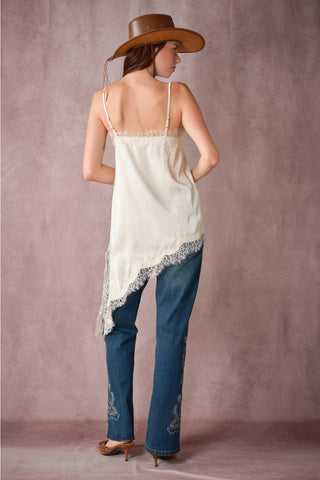 Ivory satin cami with lace trim and asymmetrical hem, styled with embroidered jeans