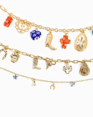 Three layered gold charm necklaces with western-themed pendants, colorful glass beads, cactus, boots, horseshoe