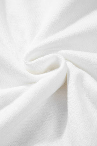 Close-up of soft white knit fabric with gentle draped folds and texture detail